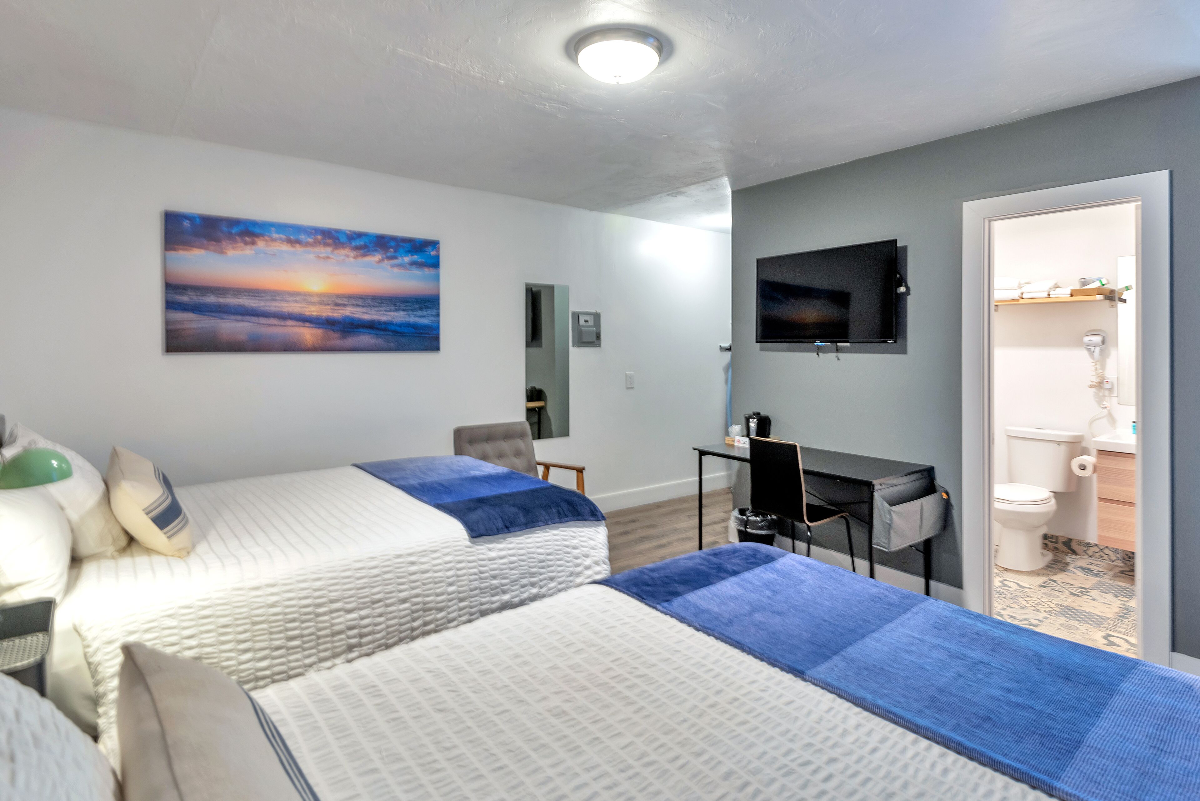 Hotelkamer met twee bedden, een bureau, een televisie en een badkamer zichtbaar door een geopende deur.