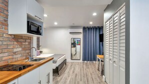 A compact kitchen with a microwave, sink, and wooden countertop. - Oasis Hotel (Fort Lauderdale)
