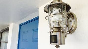 A wall-mounted light fixture with a clear glass enclosure and a metal base, positioned next to a blue door.