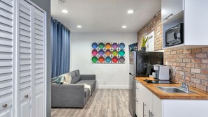 A modern kitchen with a microwave, sink, and wooden countertop. - Oasis Hotel (Fort Lauderdale)