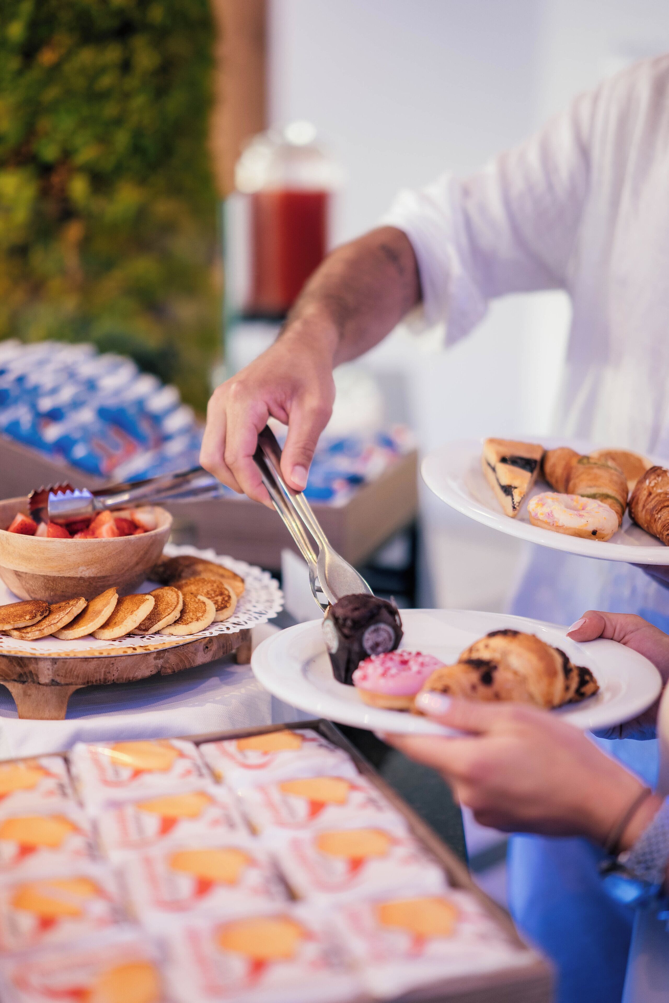 Un bufé con diversos alimentos, entre ellos panqueques, croissants y pastelería.