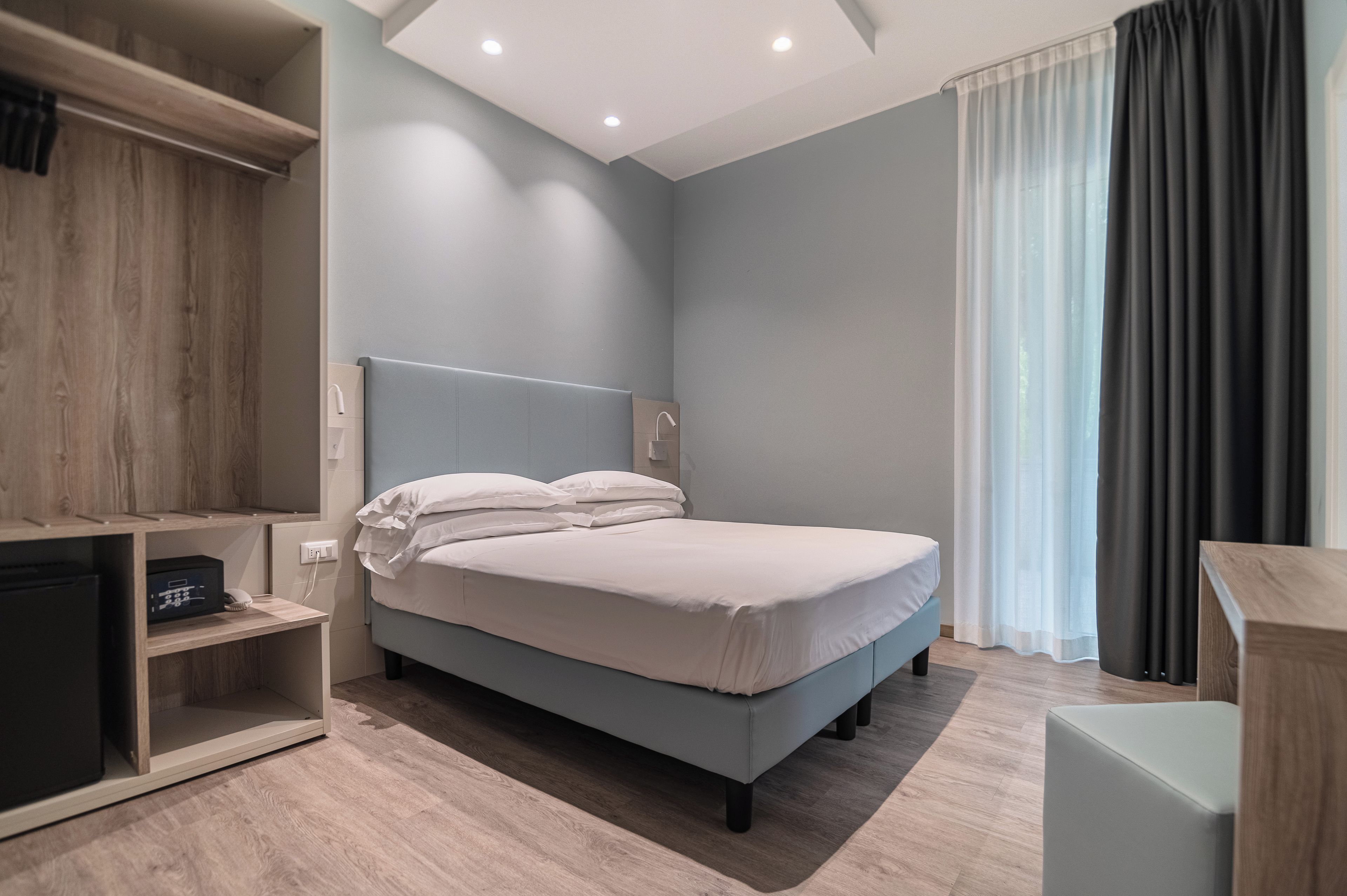 A modern bedroom with a bed, a desk, and a wardrobe.