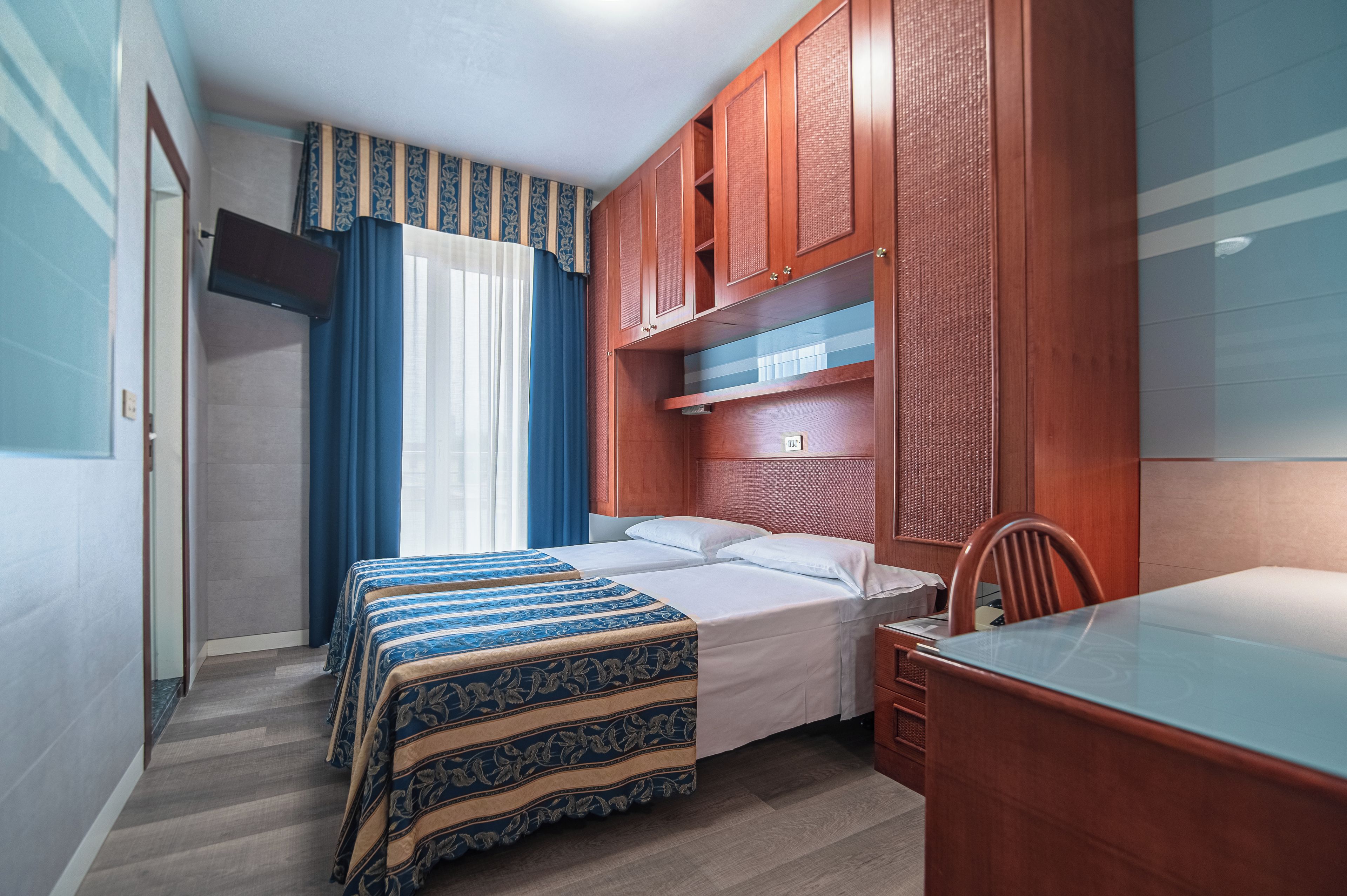 Una habitación de hotel con cama, escritorio y armario.