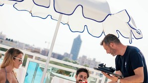 A rooftop terrace with a white umbrella, a pool, and a city view. - Hotel Colombo (Jesolo)