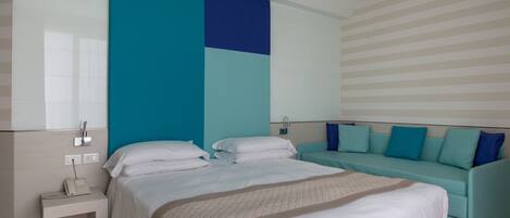 A modern hotel room with a large bed, a sofa, and a nightstand with a phone.