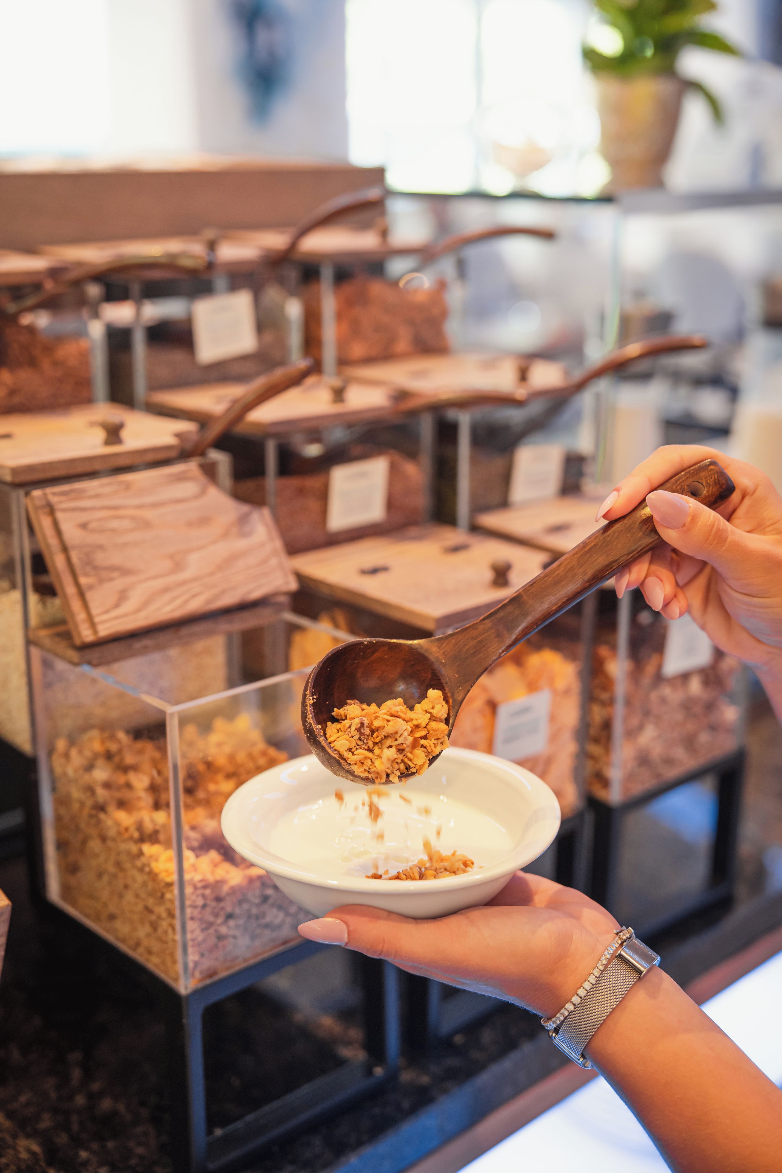 Una persona sirve granola de un tazón a otro más grande.