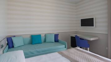 A hotel room with a bed, a sofa, a TV mounted on the wall, and a small table.