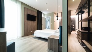 A modern hotel room with a large bed, a TV mounted on the wall, a wooden dresser, and a walk-in closet. - Hotel Colombo (Jesolo)