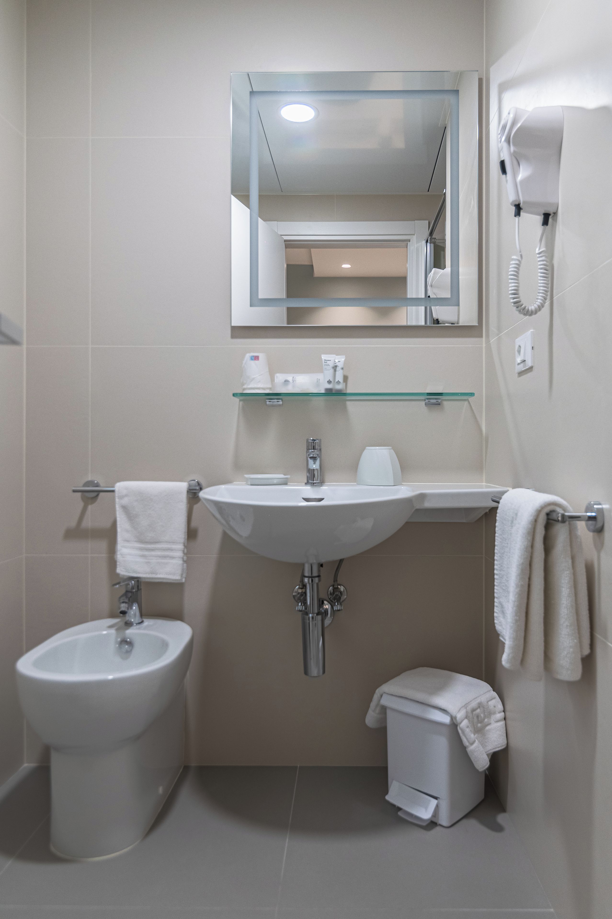 Un baño con lavabo, bidé y espejo sobre el lavabo.