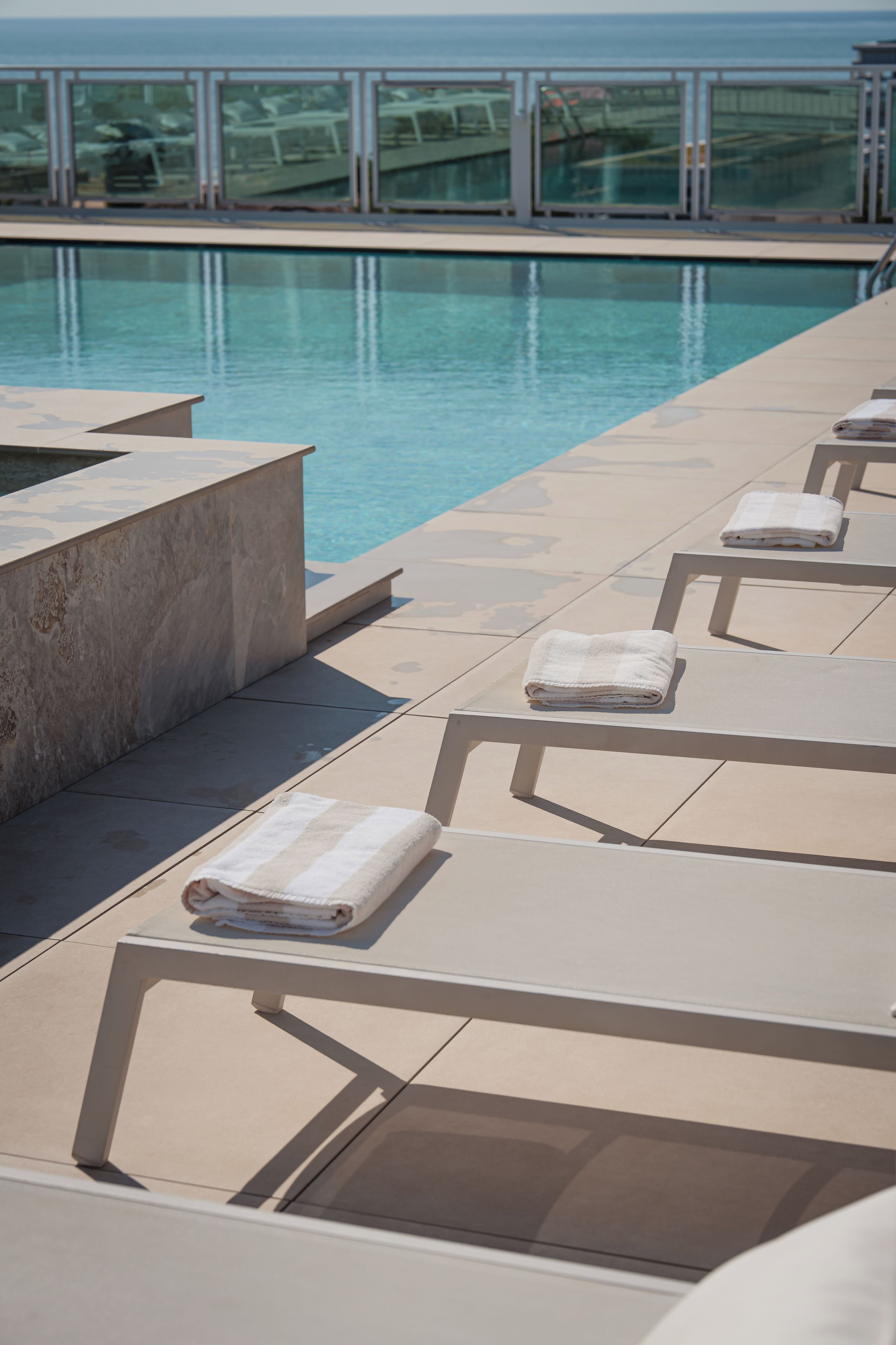 A poolside area with lounge chairs and towels, overlooking a clear pool.