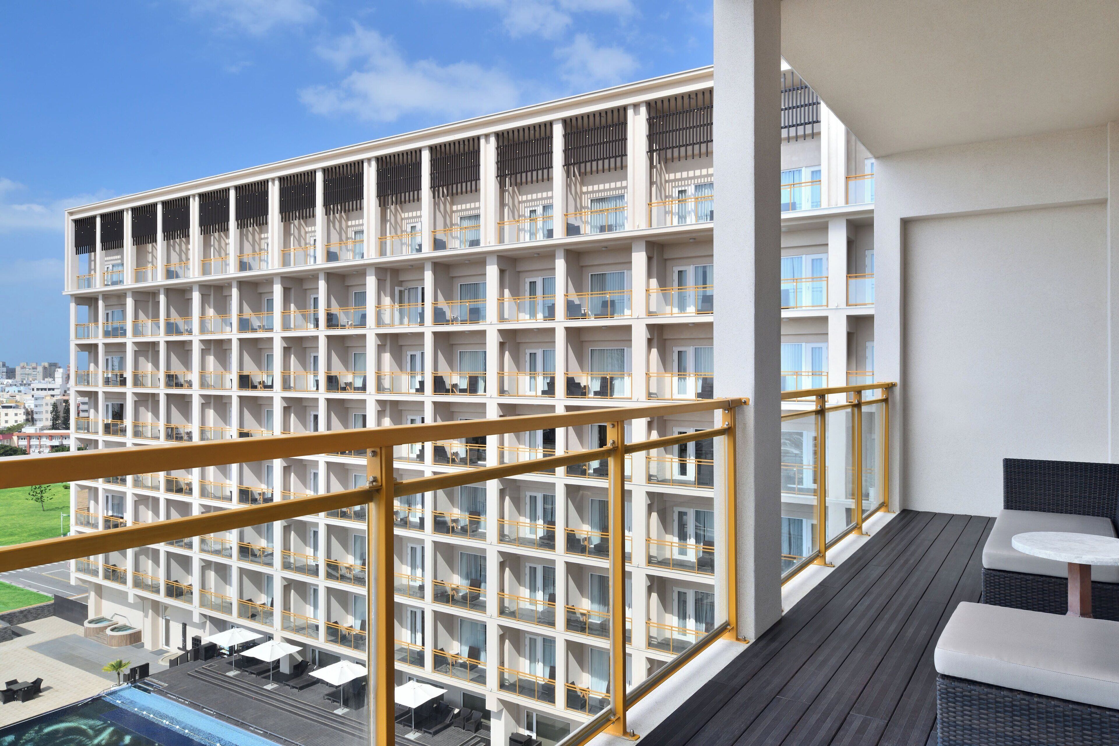 A modern hotel with a multi-story structure, balconies, and outdoor seating areas.