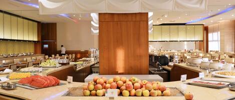 A buffet area with various food items and a large display of apples.