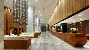 Un moderno vestíbulo de hotel con mostrador de recepción, zona de estar y una gran lámpara de araña.