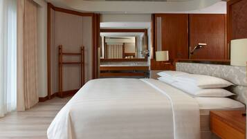 A hotel room with a large bed, wooden headboard, a nightstand, a mirror, and a wardrobe.