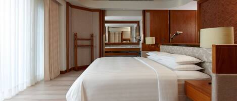 A hotel room with a large bed, wooden headboard, a nightstand, a mirror, and a wardrobe.