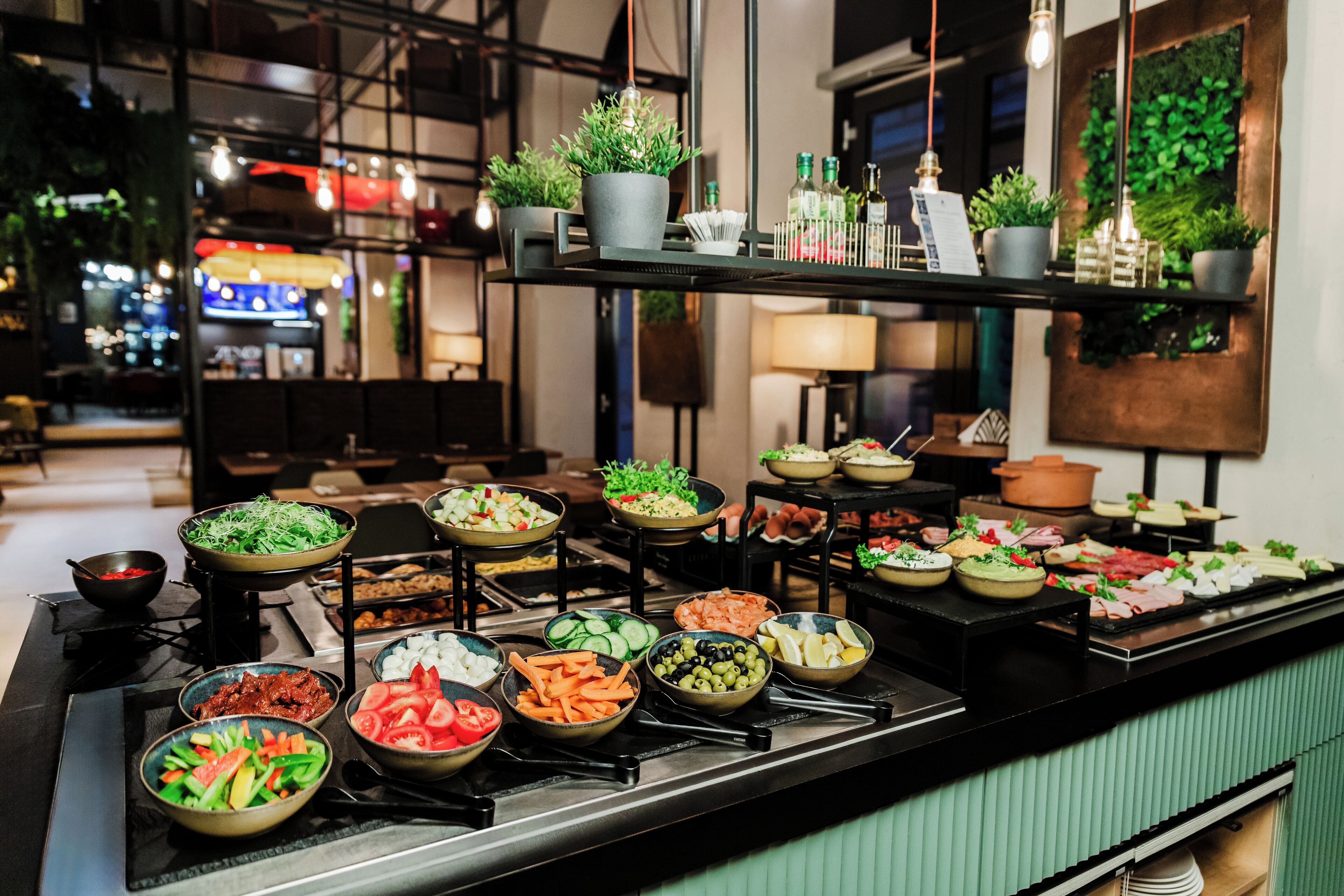 Un bufé con diversos alimentos y plantas en macetas sobre estanterías.