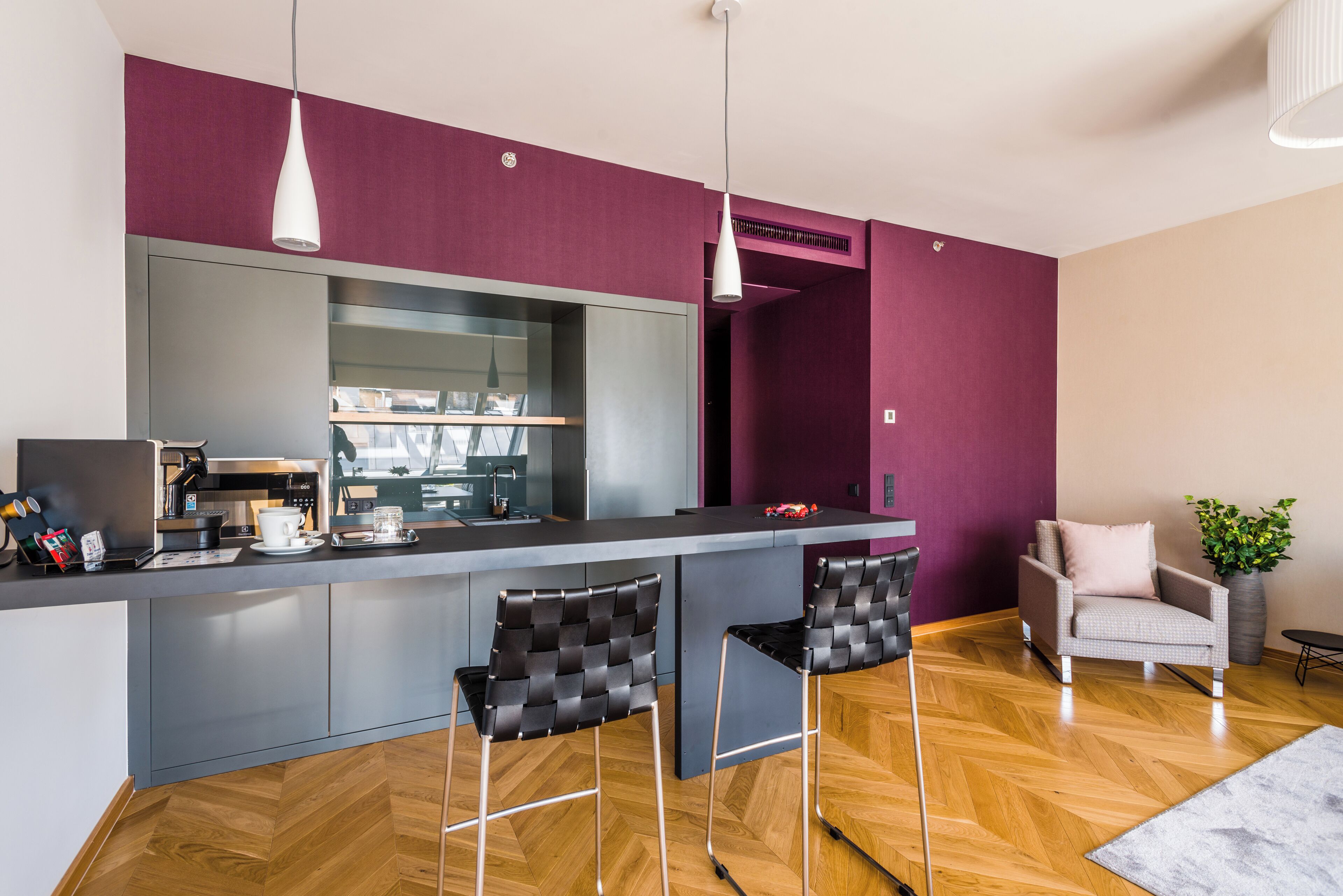 Une cuisine moderne dotée d’un îlot central, de tabourets de bar et de luminaires suspendus.