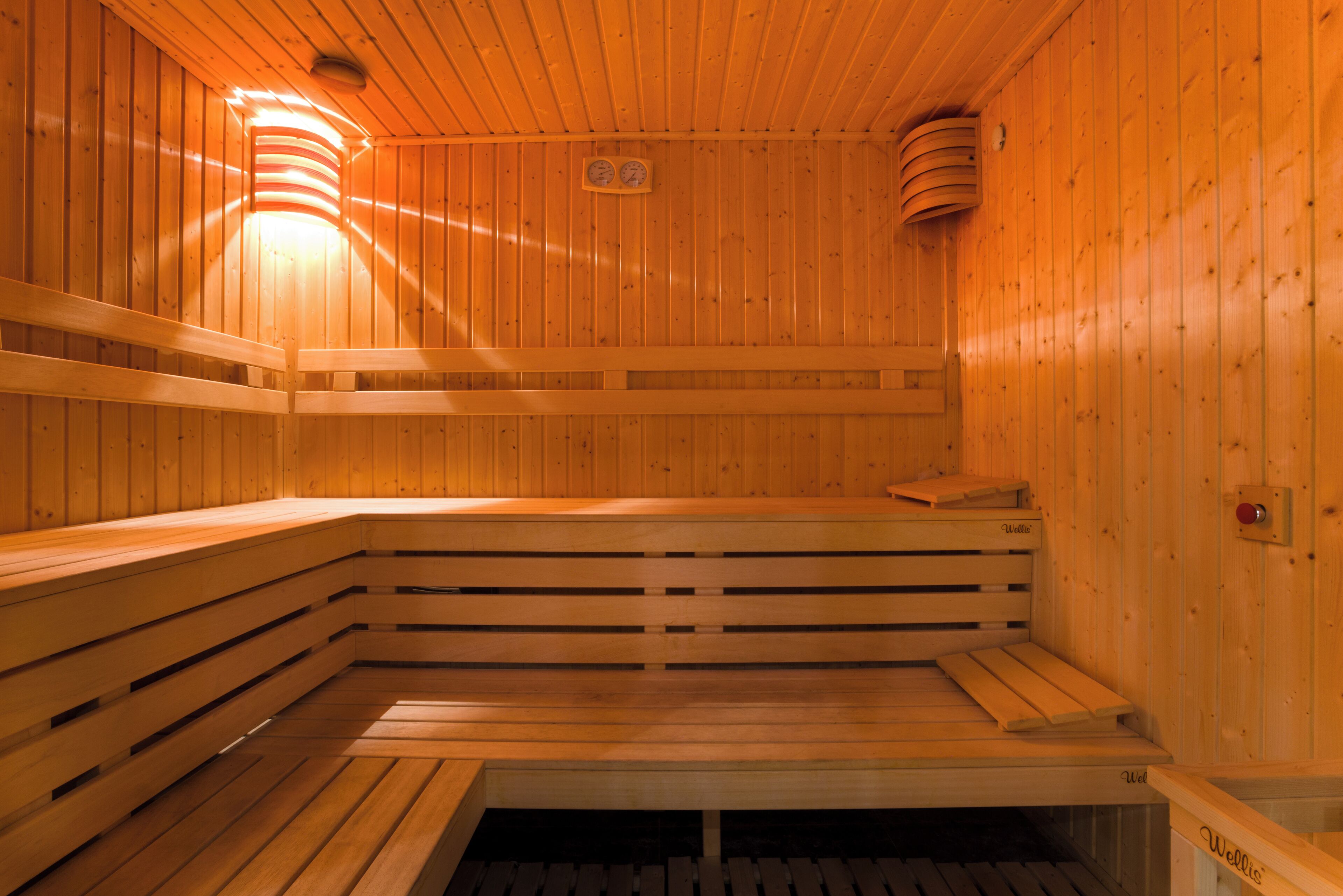 A sauna with wooden benches and benches, a visible heater, and a control panel.