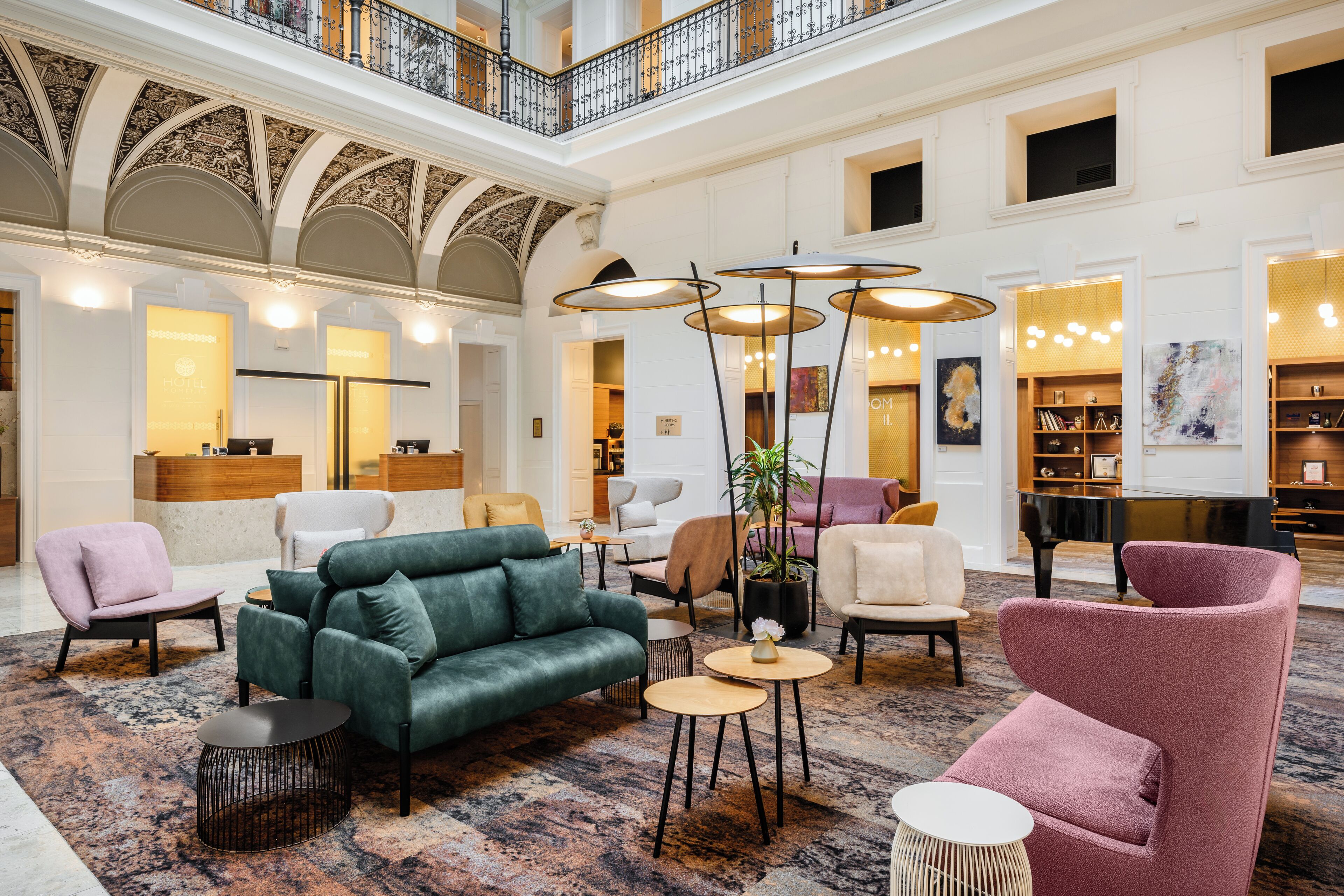 A spacious lobby with a high ceiling, ornate architectural details, and a variety of seating options including sofas and armchairs.