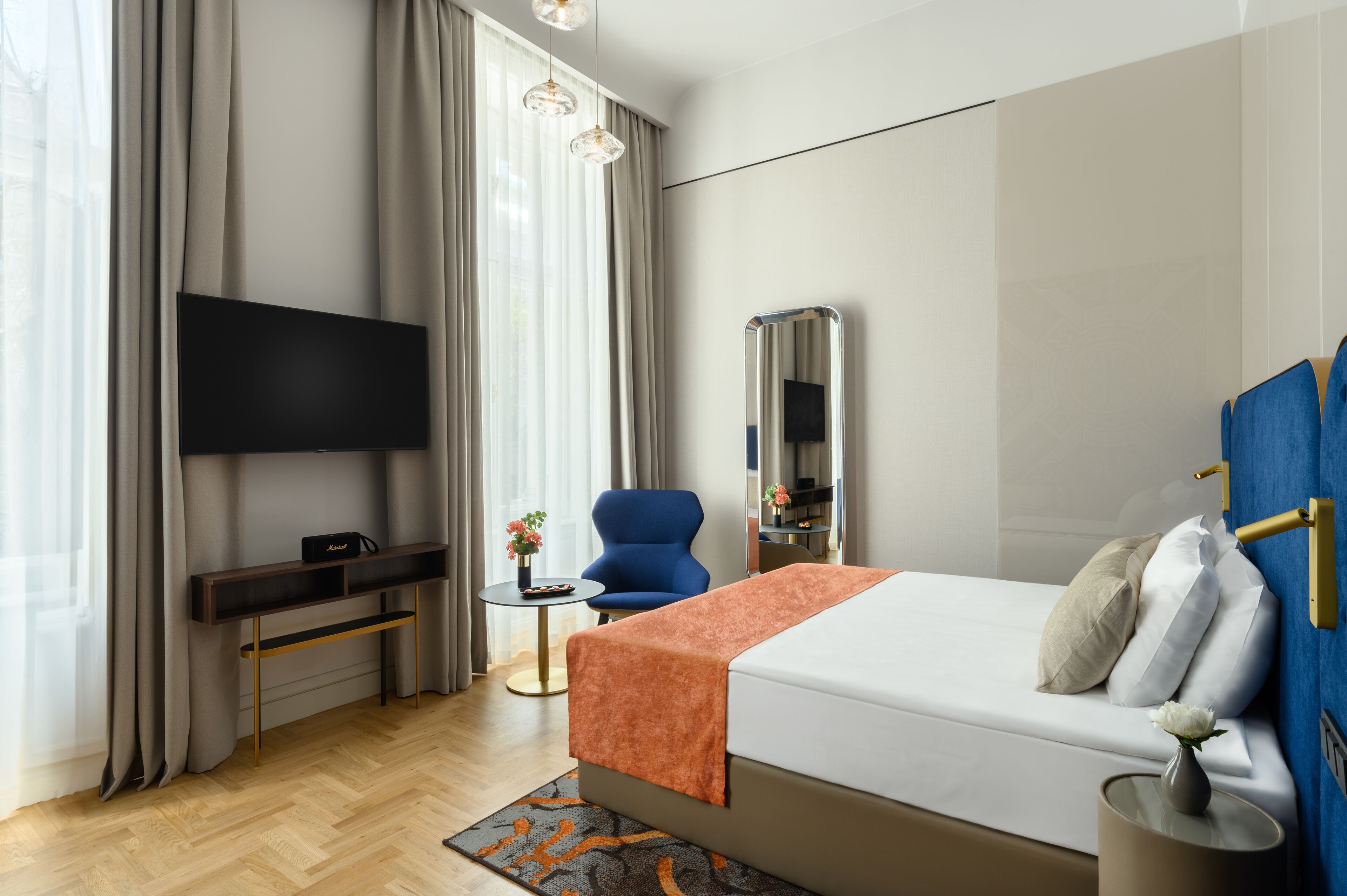 A modern hotel room with a large bed, a flat-screen TV, a desk, and a chair.