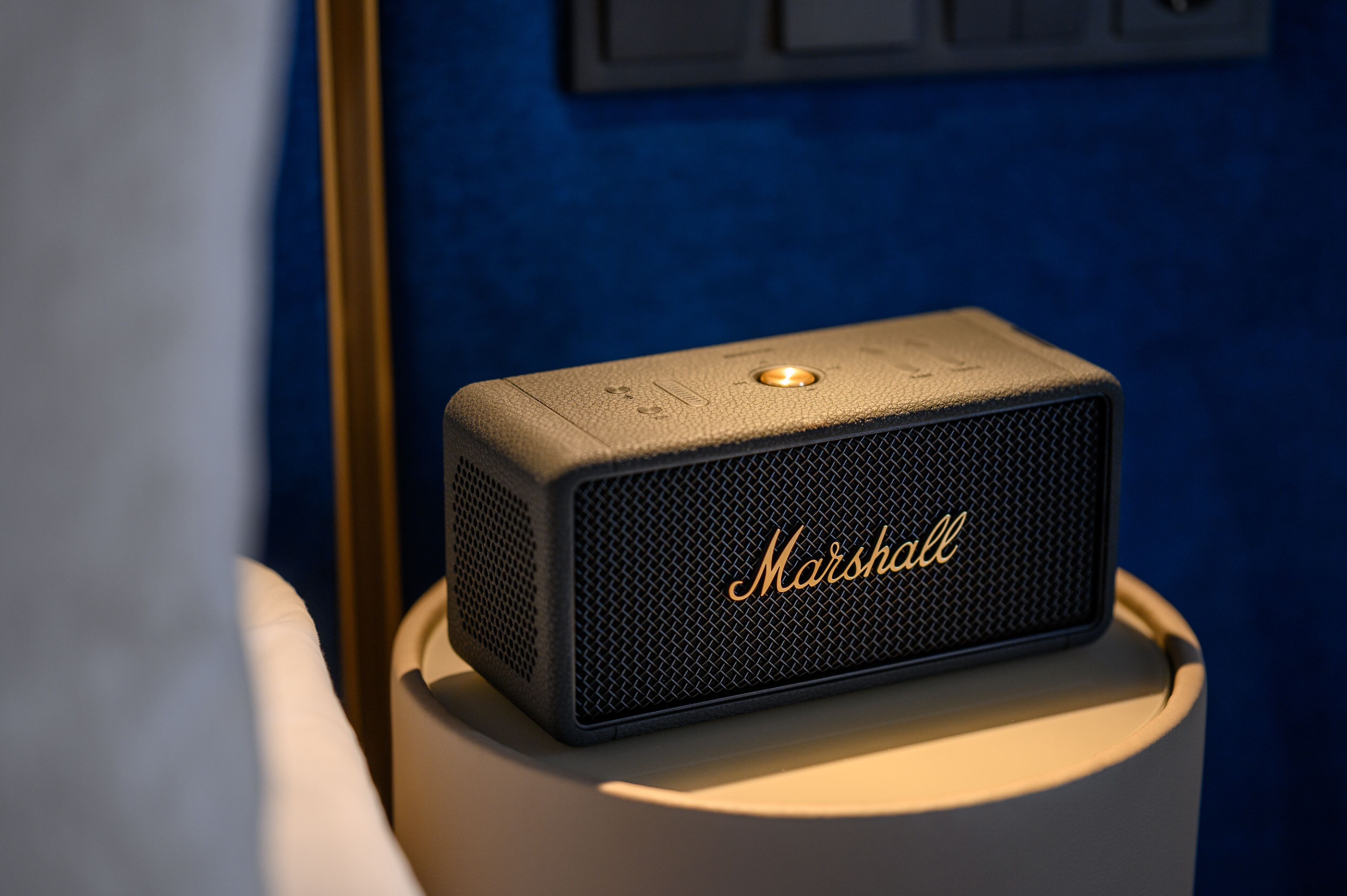 A Marshall speaker on a table with a blue wall in the background.