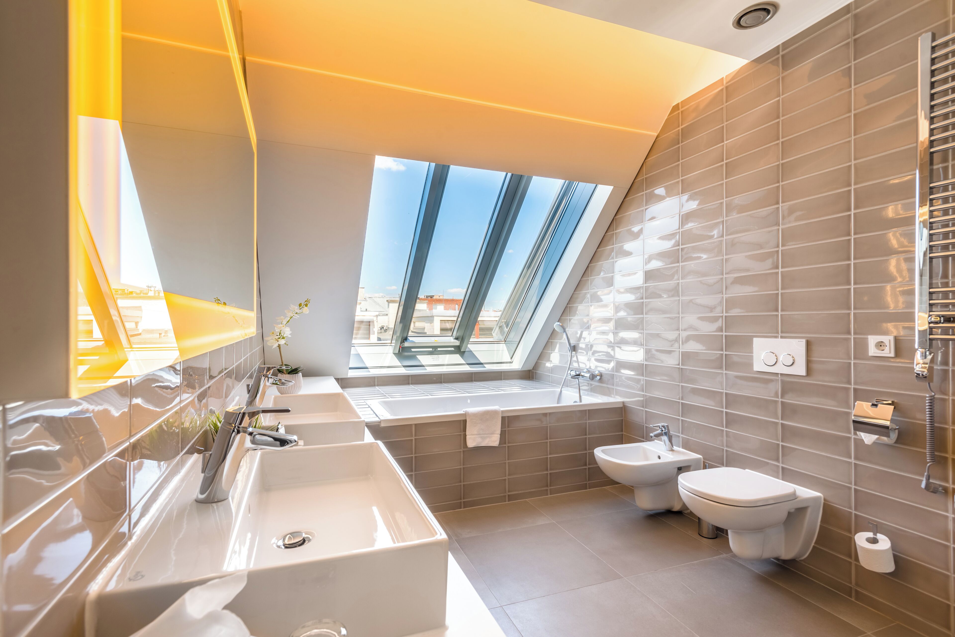 A modern bathroom with a skylight, dual sinks, a bidet, and a toilet.
