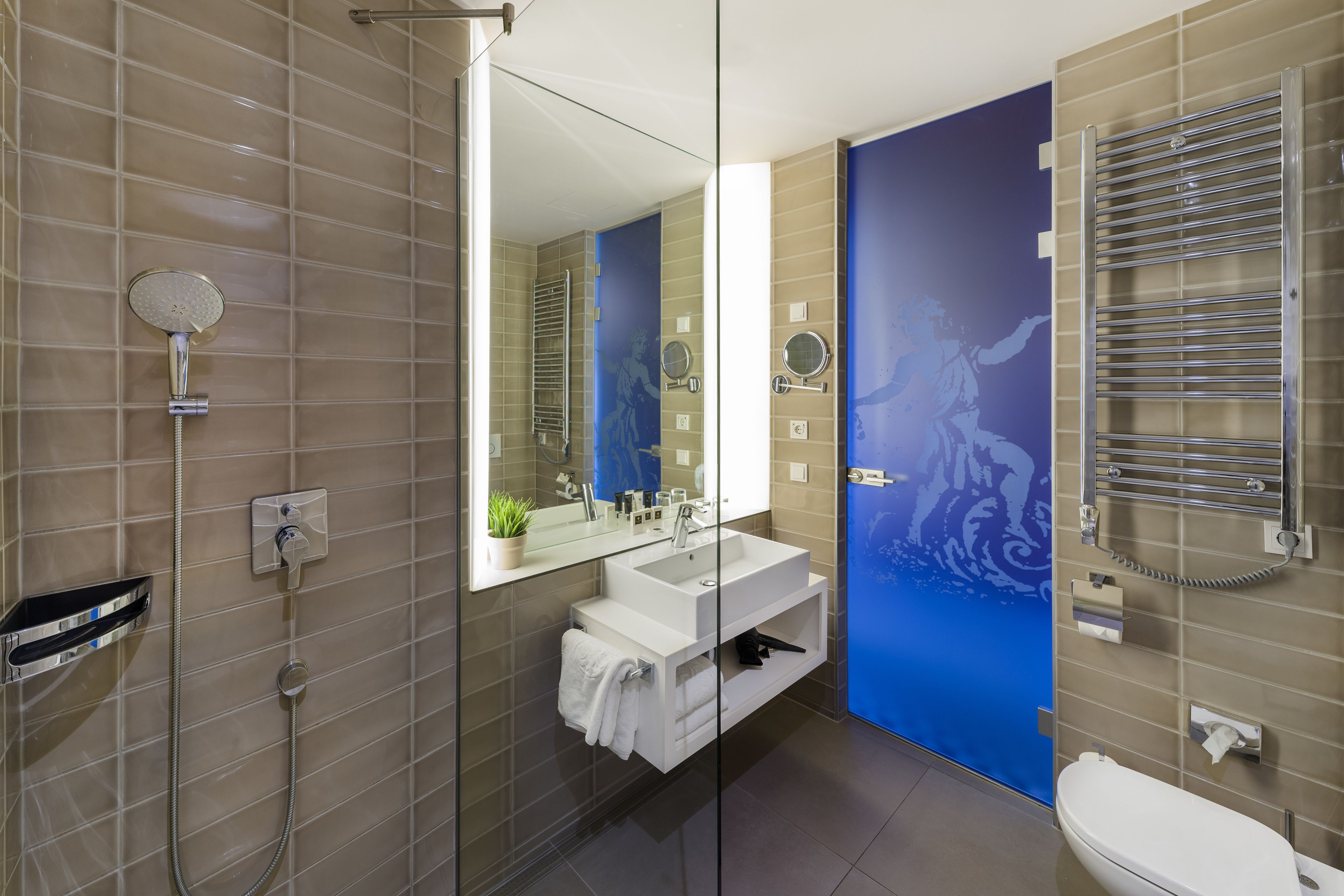 A modern bathroom with a glass-enclosed shower, a white sink, and a blue accent wall.