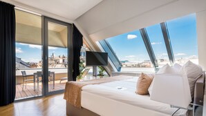 A modern hotel room with a large bed, a TV, and a balcony with a city view. - Hotel Moments Budapest (Budapest)