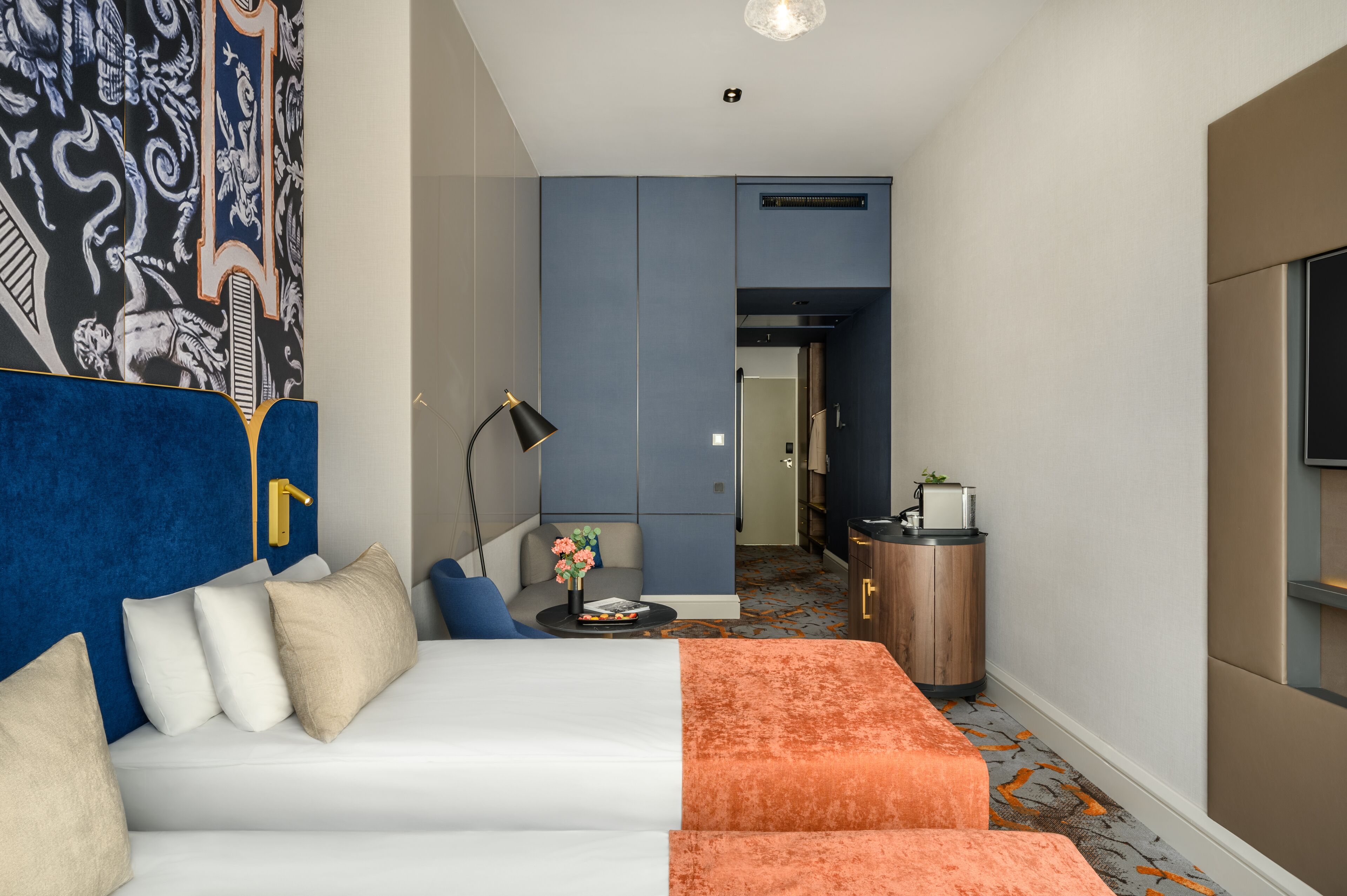A hotel room with a bed, a sofa, a desk, and a TV.