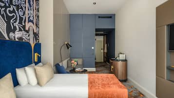A hotel room with a bed, a sofa, a desk, and a TV.