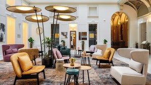 A spacious lobby with multiple seating areas, including sofas and chairs, and a central coffee table. - Hotel Moments Budapest (Budapest)