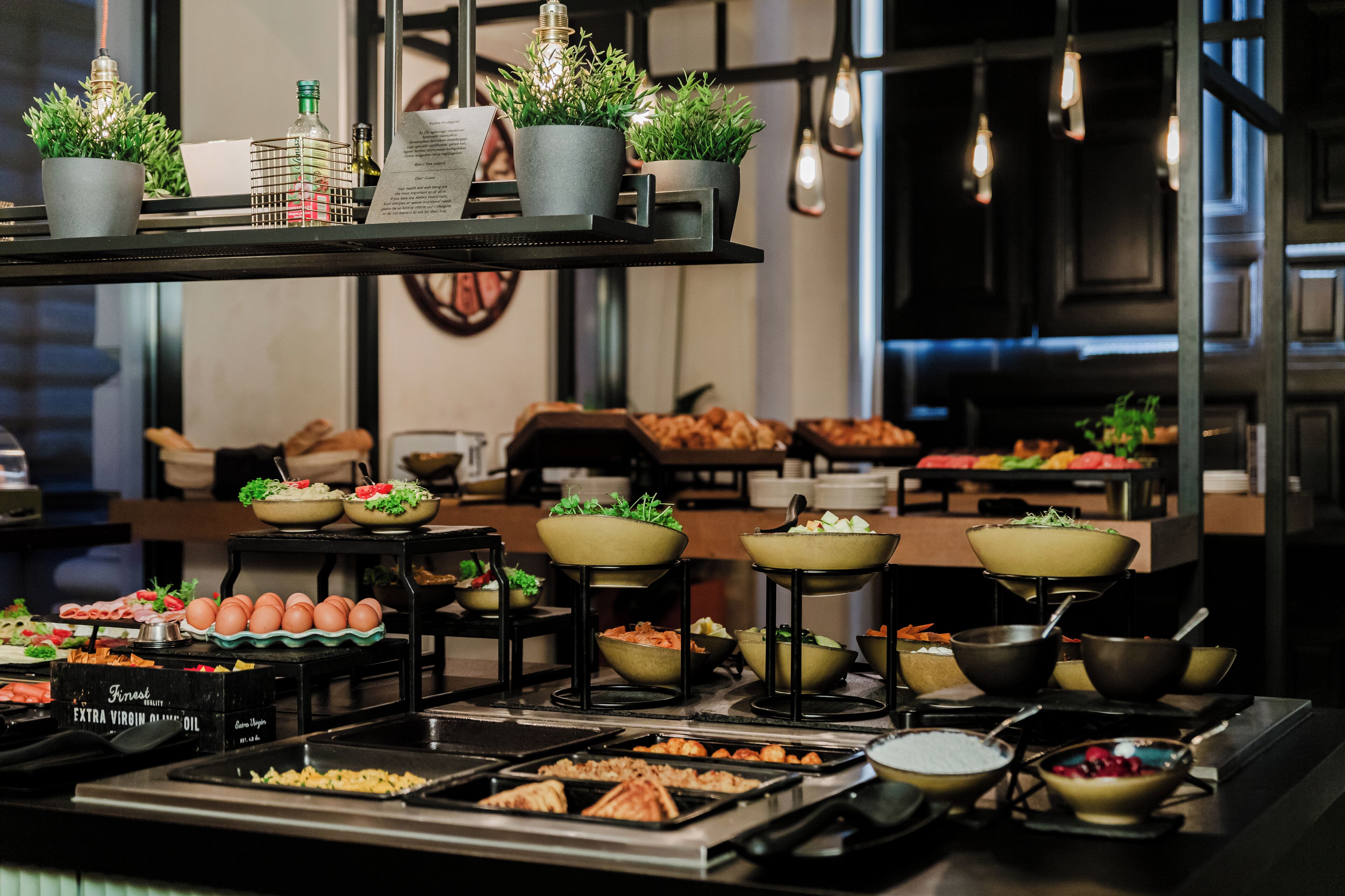 A buffet setup with various food items and decorative plants.