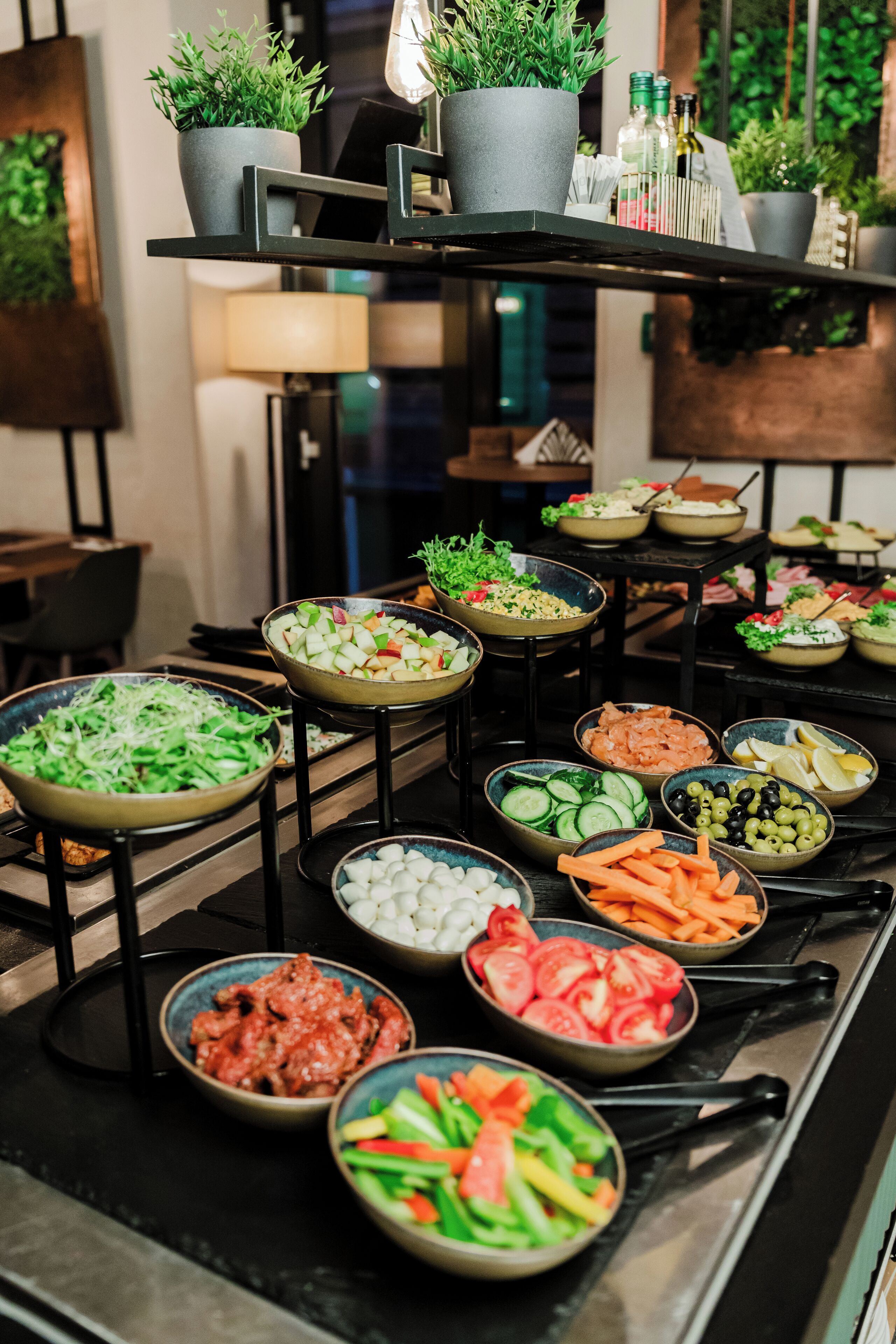 A buffet with various food items and potted plants on shelves.