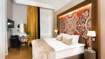 Une chambre d’hôtel avec un grand lit, un bureau avec une chaise, une télévision et une tête de lit décorative.