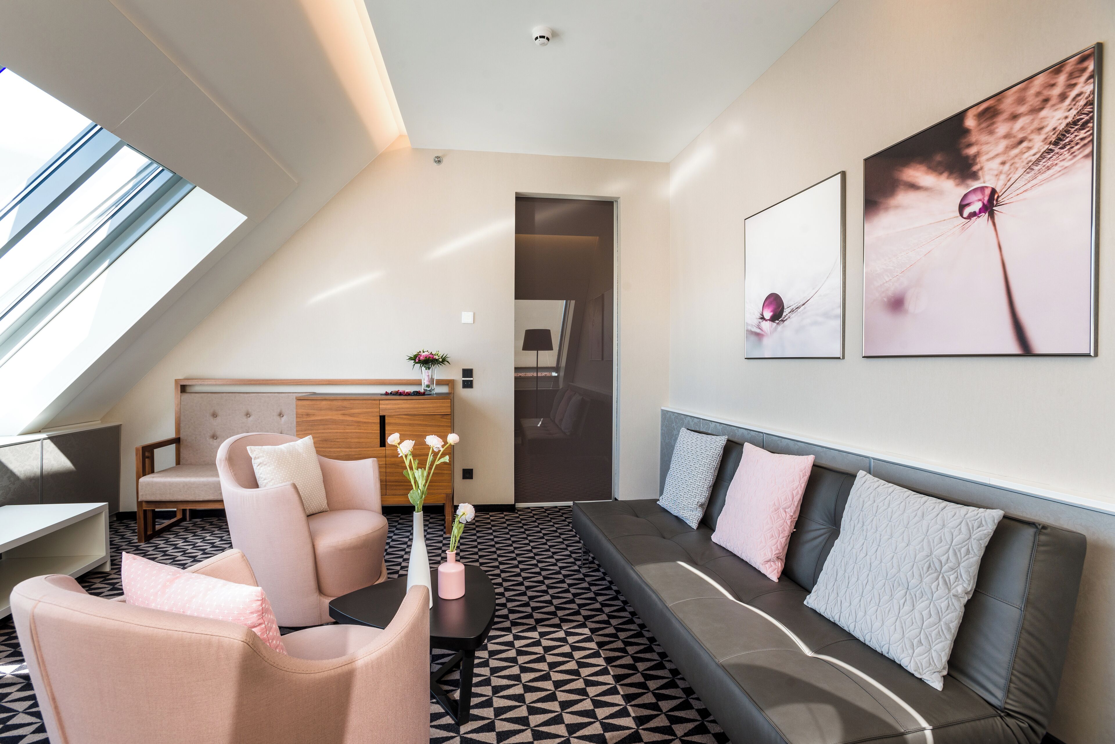 A modern living room with a sofa, chairs, a coffee table, and a vase with flowers.