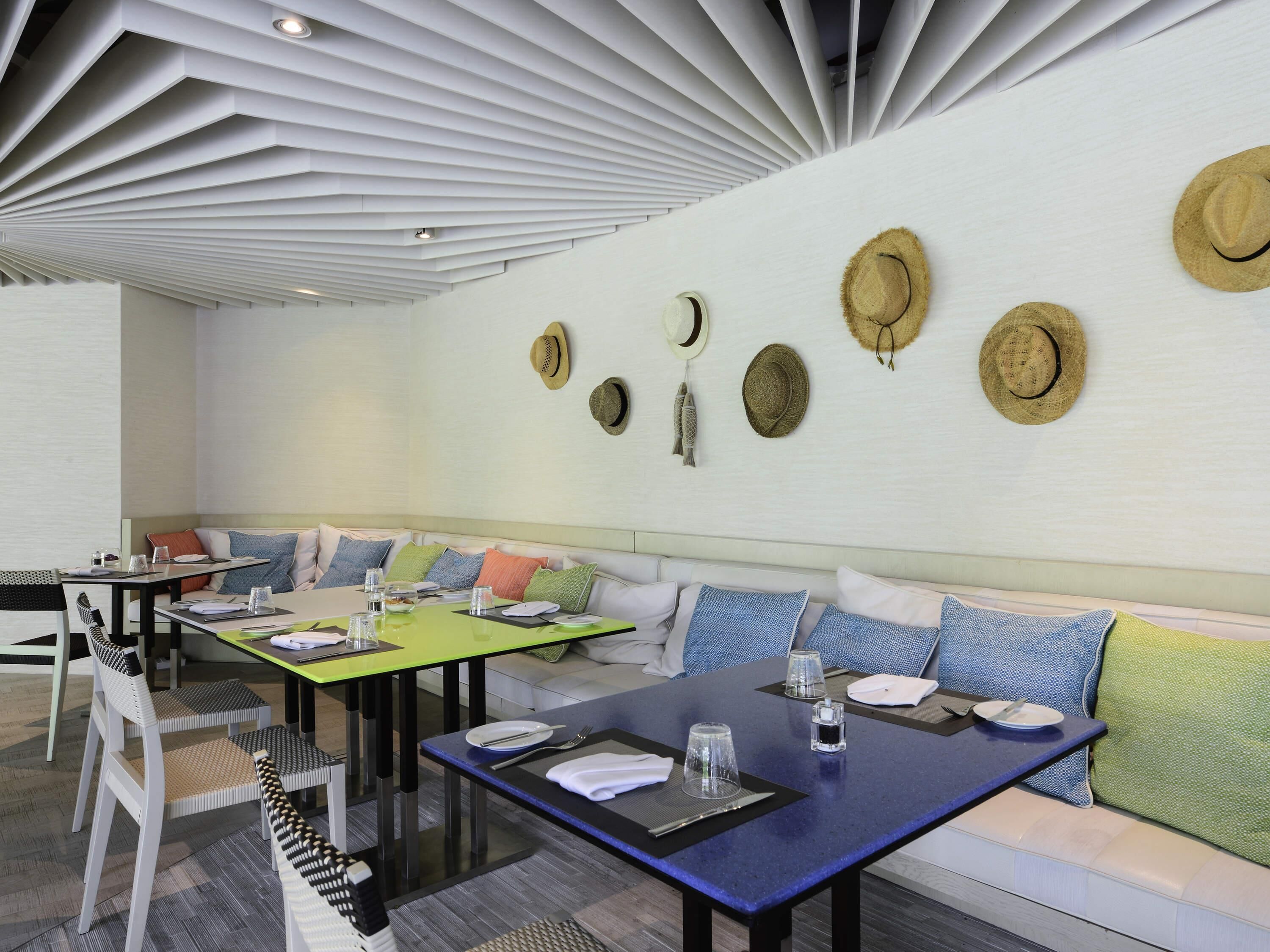 A modern dining area with a long table, chairs, and a sofa.