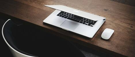 Un bureau moderne avec un ordinateur portable, une souris et une chaise.