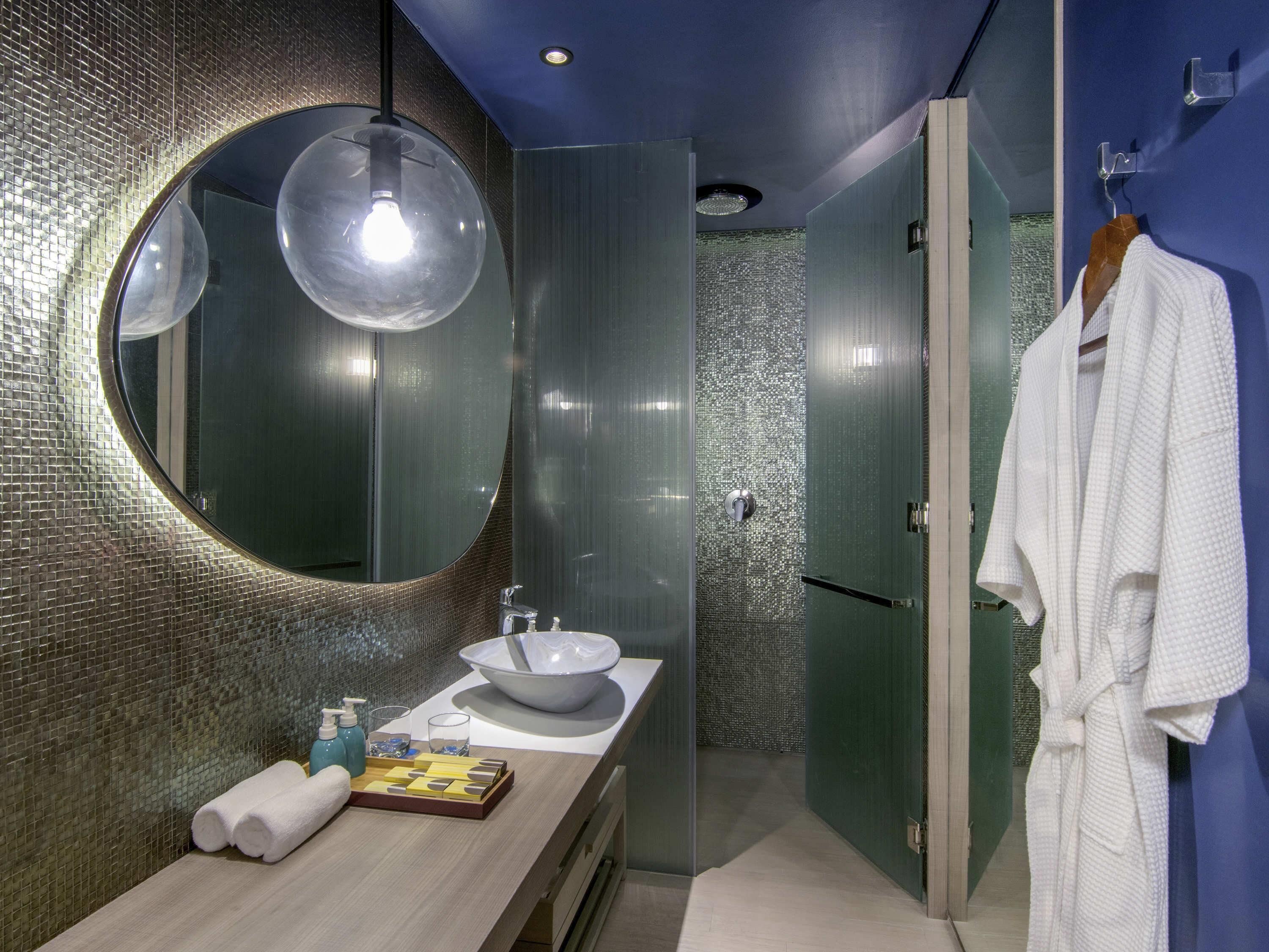 Une salle de bain moderne avec un miroir rond, un lavabo et un porte-serviettes.