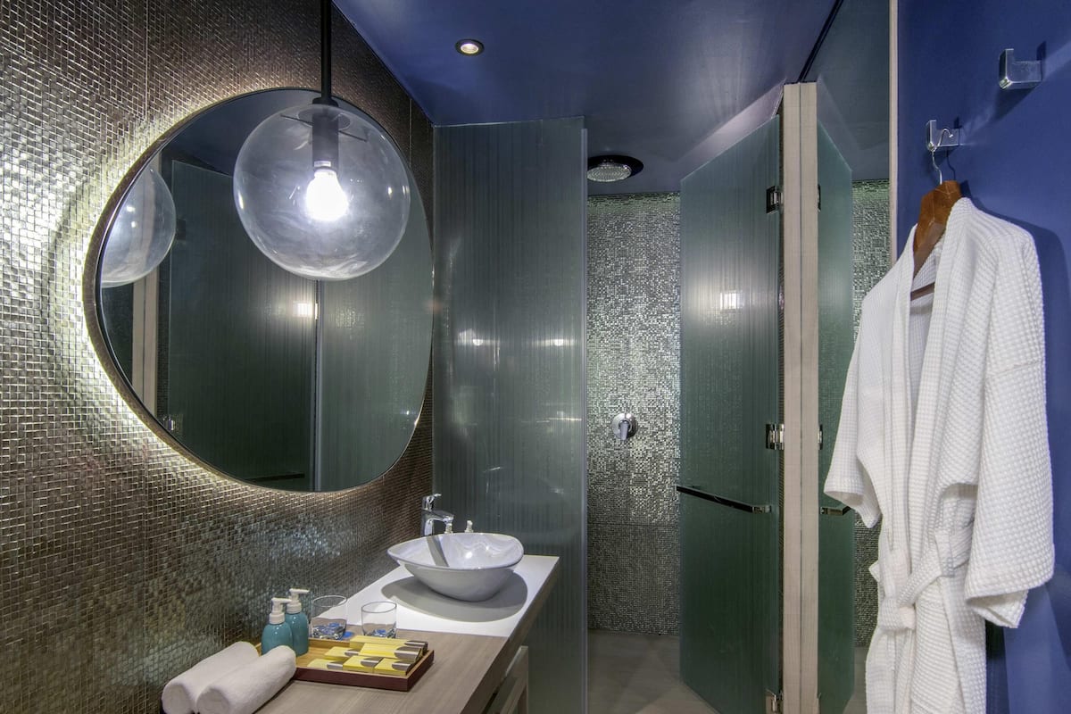 Une salle de bain moderne avec un miroir rond, un lavabo et un porte-serviettes.