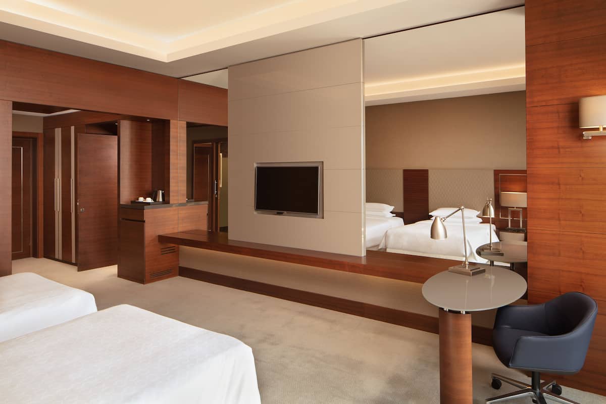 Ein Hotelzimmer mit einem großen Bett, einem Schreibtisch mit Stuhl, einem Fernseher und einem Spiegel.