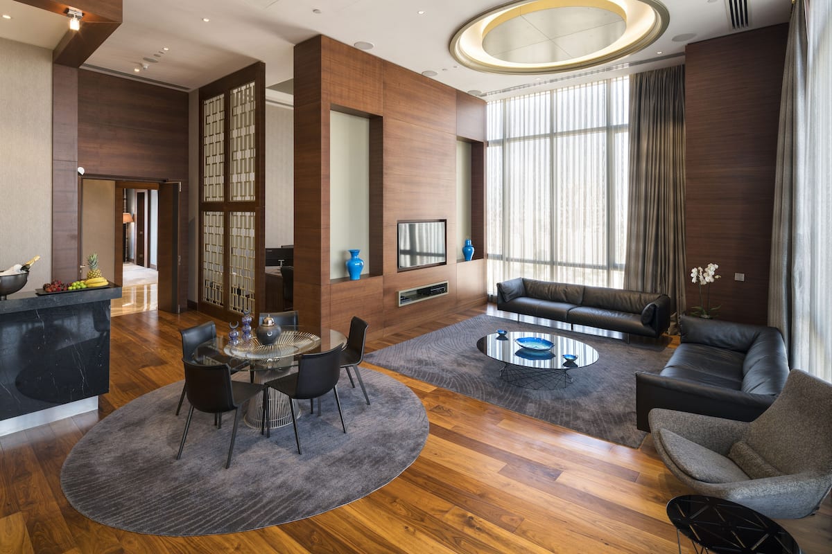 Un salon moderne avec une table basse ronde, des canapés en cuir et un coin repas comprenant une table et des chaises en verre.