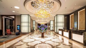 A hotel lobby with a central floral arrangement, a reception desk, and a modern chandelier. - Sheraton Grand Istanbul Atasehir (Istanbul)