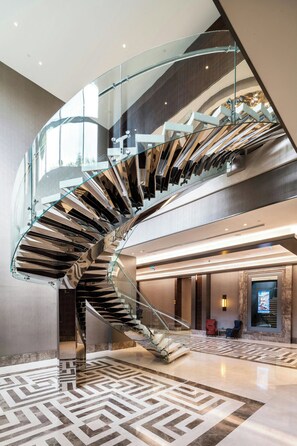 A modern interior with a curved glass staircase connecting two floors. - Sheraton Grand Istanbul Atasehir (Istanbul)