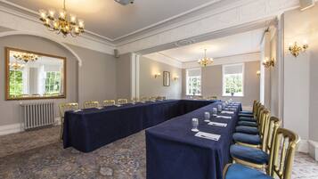 A conference room with a long table, chairs, and chandeliers.