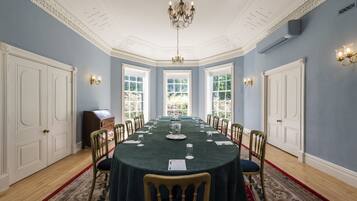 Uma sala de jantar formal com uma mesa comprida, cadeiras e um lustre.
