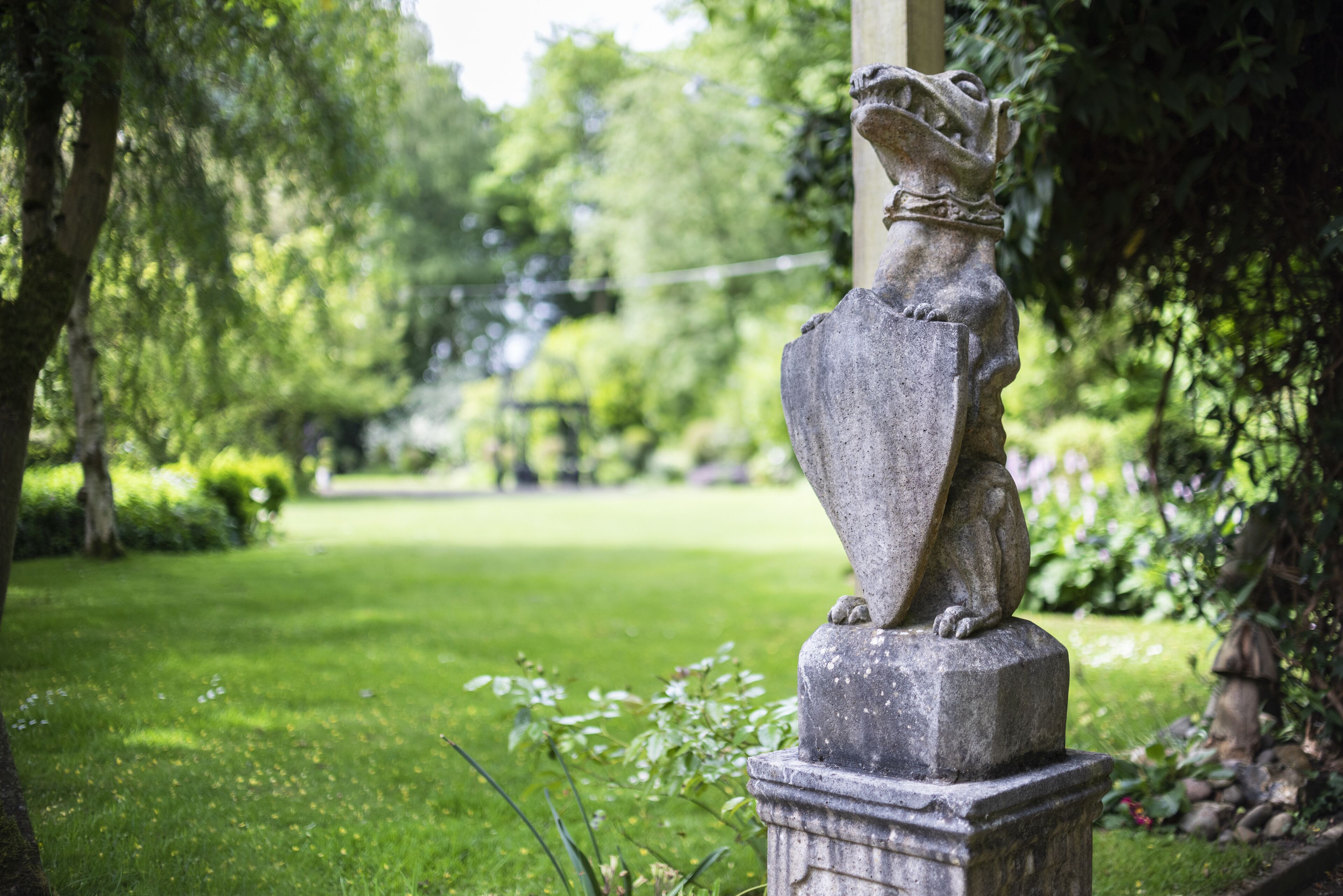 Una estatua de piedra en un jardín con un sendero despejado y abundante vegetación.