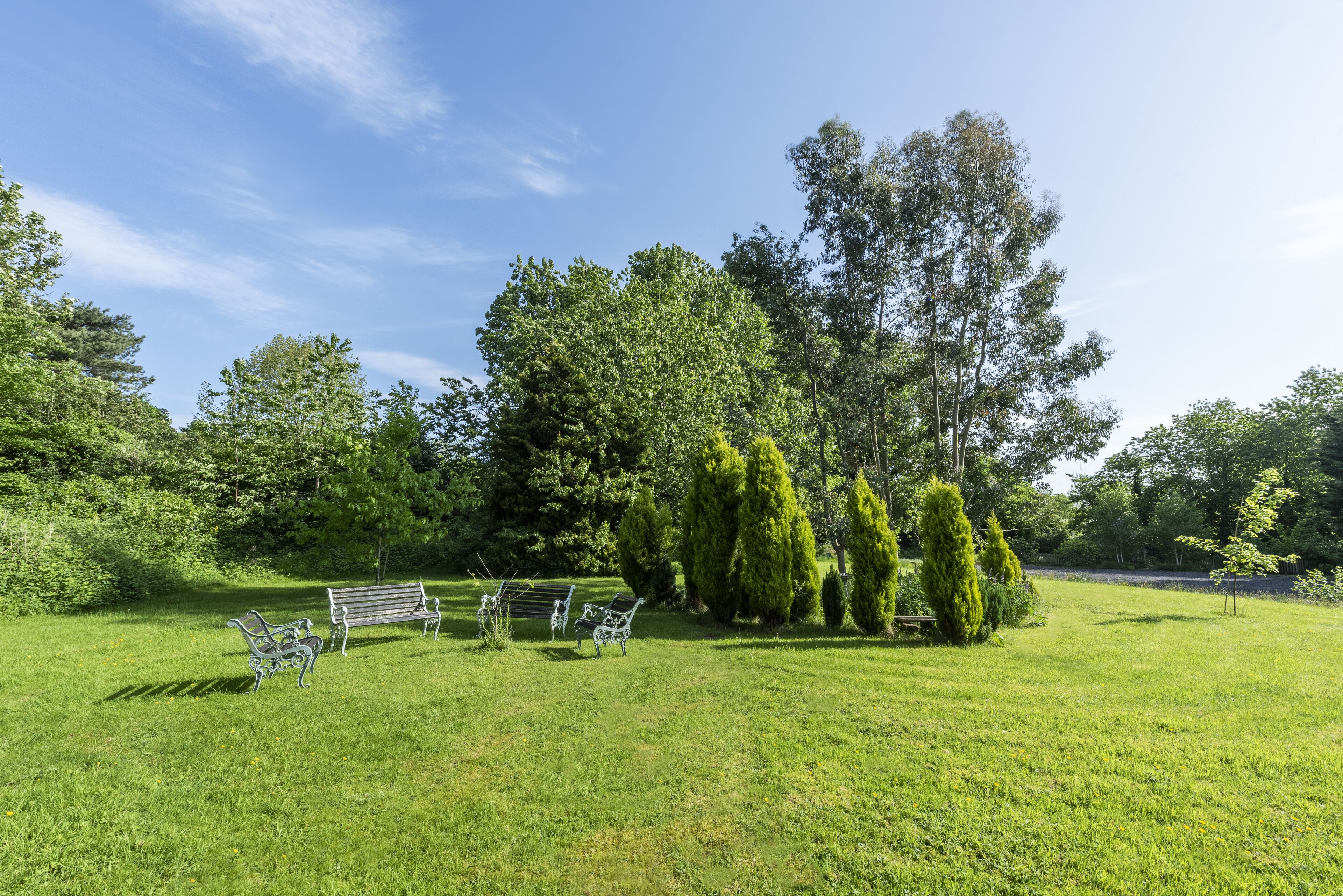 A grassy park area with a bench and metal sculptures.