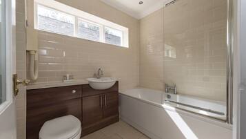 A bathroom with a toilet, sink, vanity, and bathtub.