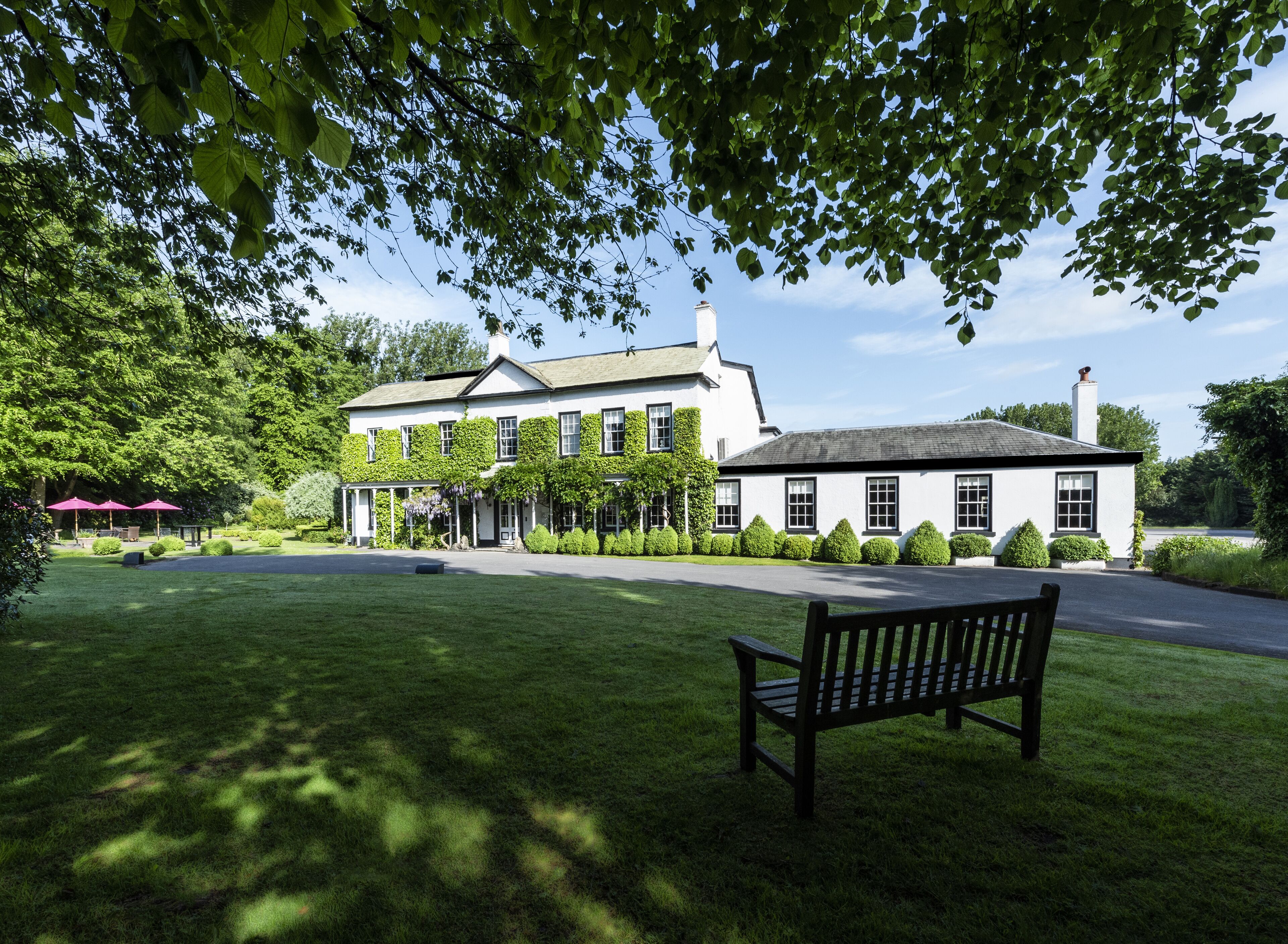 A large, white building with a traditional design, surrounded by well-maintained lawns and trees.