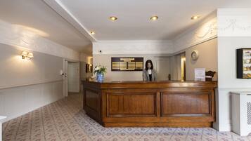 A reception area with a wooden reception desk, a wall-mounted clock, and a bulletin board.